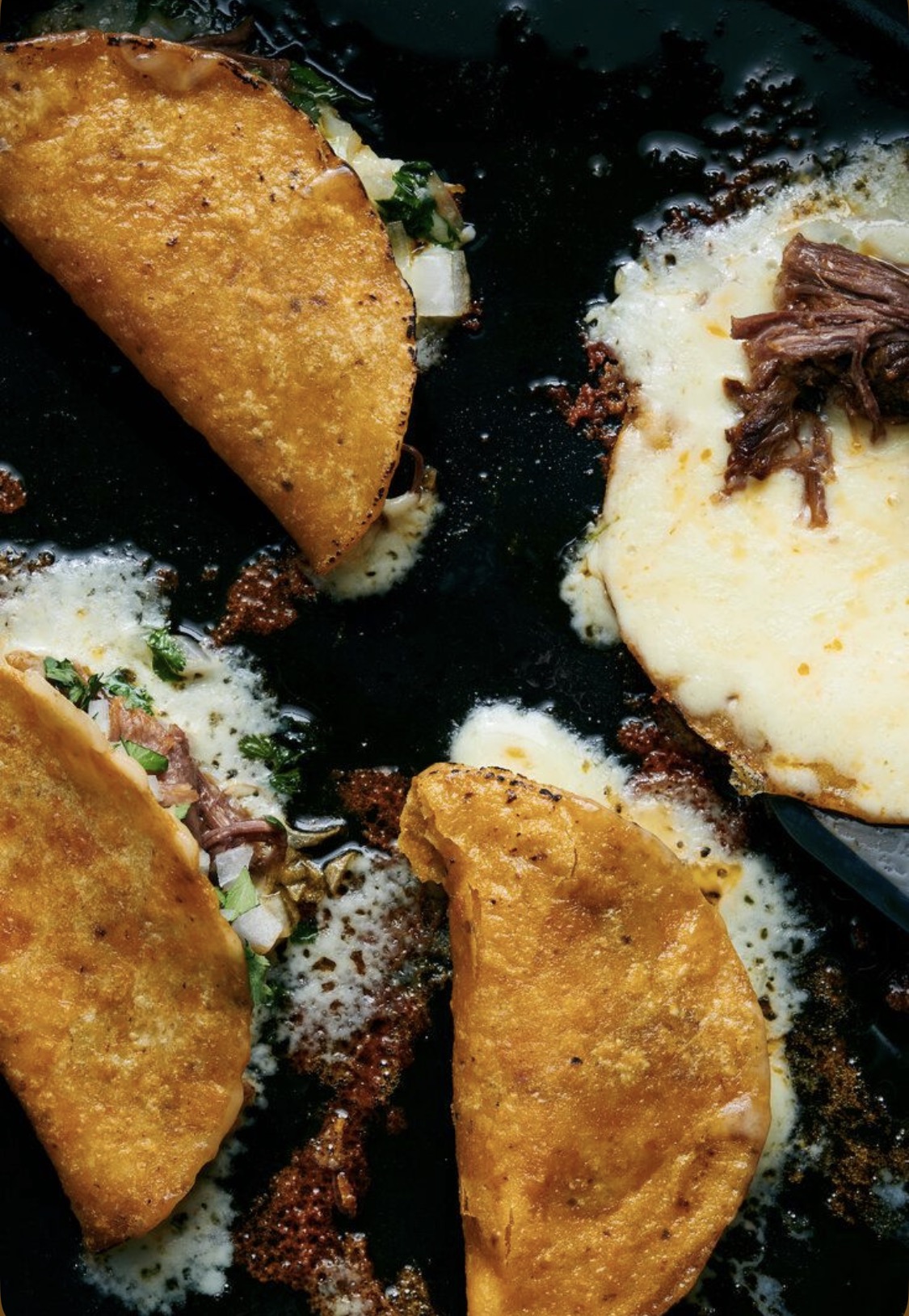 Crispy birria tacos seared on a hot skillet with bubbling cheese and braised beef — The Vaquero.
